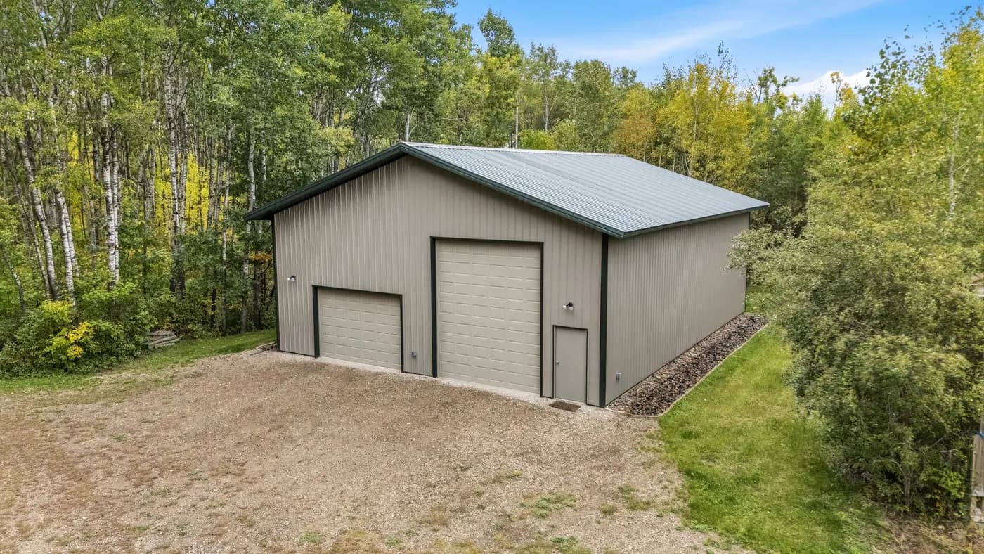 Sherman pole building with two overhead garage doors on a wooded property