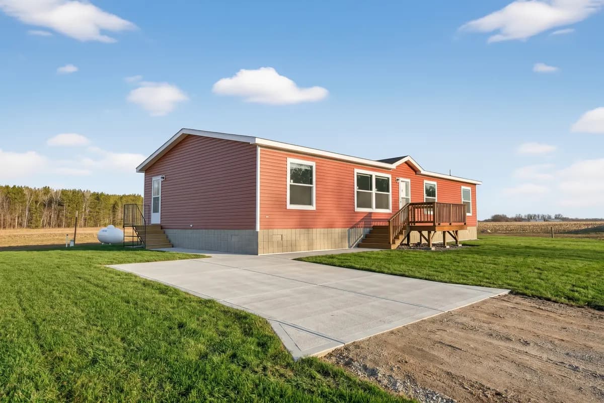 Illustration of a red modular home with white trim, a wood front deck, lawn, and concrete walkway